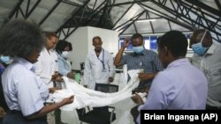 A health inspection officer shows doctors how to use protective equipment before they head to a ward at Mbagathi hospital for patients under quarantine and confirmed cases with the new coronavirus, at Kenyatta National Hospital in Nairobi, Kenya Thursday,