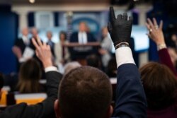 FILE - Reporters raise their hands to ask President Donald Trump questions during a press briefing with the coronavirus task force, at the White House, in Washington, March 16, 2020.