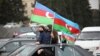 З національними прапорами азербайджанці святкували повернення своїх територій у Баку, 1 грудня 2020 року.  Тоді президент Азербайджану Ільхам Алієв назвав відновлення контролю над Лачинським районом та іншими територіями «історичним досягненням».