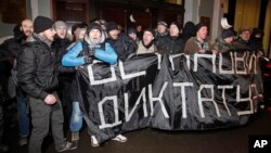 Des manifestants de l'opposition russe brandissent une banderole disant «arrêtez la dictature» lors d'un rassemblement anti-gouvernemental devant le Comité central des élections au centre-ville de Moscou, en Russie, le 14 février 2012.