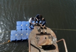 FILE - Laborers carry out maintenance work at Benghazi port, Libya, Oct. 3, 2017.