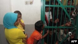 A woman and her children visit their husband and dad of Myanmar Rohingya Muslims at the court's detention house in Medan, North Sumatra, Dec. 4, 2013, before the verdict.