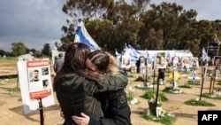 FILE - Two women react while visiting the site of the Supernova music festival near Kibbutz Reim, southern Israel, on February 19, 2024.