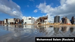 Pengungsi Palestina berkumpul di kamp tenda yang terendam banjir akibat hujan lebat di Khan Younis, Jalur Gaza selatan, 22 September 2024. (Foto: REUTERS/Mohammed Salem)