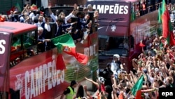 Les joueurs de l’équipe nationale portugaise montés sur un bus à toit ouvert, sont accueillis par une foule des supporters en liesse dans les rues de Lisbonne, Portugal, 11 juillet 2016. epa/ SETVEN GOVERNO