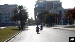 People ride motorcycles on a street empty of traffic near the National Palace in Port-au-Prince, Haiti, July 7, 2021. Gunmen assassinated Haitian President Jovenel Moise and wounded his wife in their home early Wednesday. 