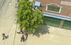 A security officer kicks a man lying on the street in Sanchaung, Yangon, Myanmar, March 27, 2021 in this still image taken from video.