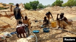 FILE - Informal gold miners are seen taking a break from work under the midday sun at an artisanal mining site near Dano, southern Burkina Faso, May 5, 2020. 