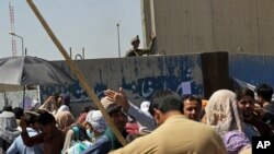 Soldados estadounidenses se encuentran dentro del muro del aeropuerto mientras cientos de personas reúnen cerca de un puesto de control de evacuación en el perímetro del aeropuerto en Kabul, Afganistán, el jueves 26 de agosto de 2021.