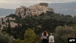 FILE - People visit the Pnyx Hill in Athens overlooking the ancient Acropolis, May 29, 2020.