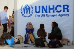 FILE - Syrian displaced families, who fled violence after the Turkish offensive in Syria, sit at a refugee camp in Bardarash on the outskirts of Dohuk, Iraq, Oct. 25, 2019.