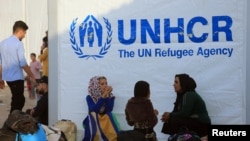 Syrian displaced families, who fled violence after the Turkish offensive in Syria, sit at a refugee camp in Bardarash on the outskirts of Dohuk, Iraq, Oct. 25, 2019.