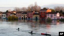 Canoeists sail their way as water reaches the houses after the Ticino river overflowed its banks, in Pavia, Italy, Nov. 25, 2019.