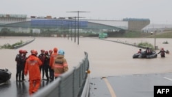 South Korean emergency workers search for survivors on a flooded road leading to an underground tunnel where some 19 cars were trapped by flood waters after heavy rains in Cheongju on July 15, 2023.