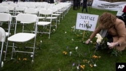 A woman places a rose next to 298 empty chairs, each chair for one of the 298 victims of the downed Malaysia Air flight MH17, in a park opposite the Russian embassy in The Hague, Netherlands, March 8, 2020.