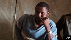 Elected chief of a displacement camp, Witonze Nzambonipa, talks during an interview in Mweso, DRC, Jan. 27, 2015. The wobbly white tarp tents once constructed for people fleeing a violent Rwandan Hutu rebel group have gradually been replaced by more solid huts of branches, banana leaves and mud. 