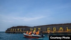 Aktivis Greenpeace menulis Coral not Coal di lambung tongkang batubara di Karimunjawa, sebagai ilustrasi. (Foto: Greenpeace Indonesia)