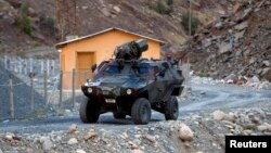 FILE - A Turkish military armored personnel carrier drives past a small patrol base in the mountains of Cukurca in southeastern Turkey, near the Iraqi border, Oct. 21, 2011.