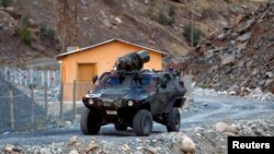 FILE - A Turkish military armoured personnel carrier drives past a small patrol base high in the mountains of Cukurca near the Iraqi border in southeastern Turkey.