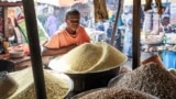 Chinedu Nwuzor waits for costumers while selling grains, legumes and flours in his stall at a market in the Obalende area of Lagos on December 18, 2023.