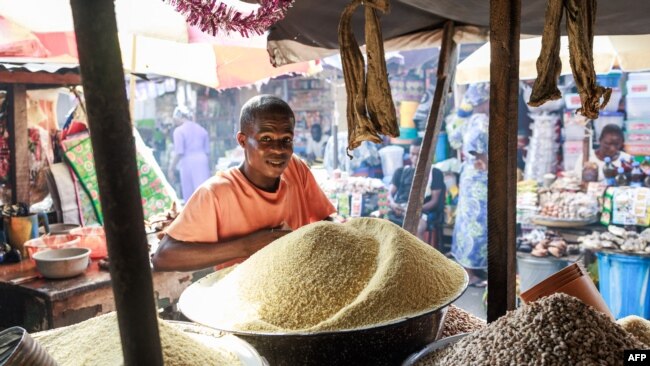 FILE - Chinedu Nwuzor waits for costumers while selling grains, legumes and flours in his stall at a market in the Obalende area of Lagos on December 18, 2023.