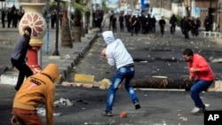 Egyptian protesters throw stones at riot police during clashes near a state security building in Port Said, March 7, 2013.