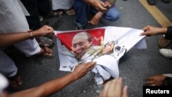 Muslims burn a picture of Burma's president Thein Sein as they protest in front of Burma's embassy in Bangkok, June 21, 2012. 