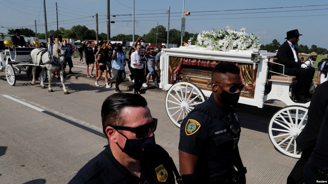 Police officers walk next to the horse-drawn carriage carrying the casket containing the body of George Floyd to Houston Memorial Gardens cemetery in Pearland, Texas, June 9, 2020.