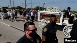Police officers walk next to the horse-drawn carriage carrying the casket containing the body of George Floyd to Houston Memorial Gardens cemetery in Pearland, Texas, June 9, 2020.