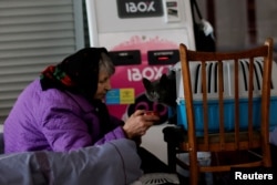 A woman feeds a cat in a complex converted to a temporary shelter for people fleeing Russia's invasion of Ukraine, in Dnipro. April 14, 2022. (REUTERS/Ueslei Marcelino)