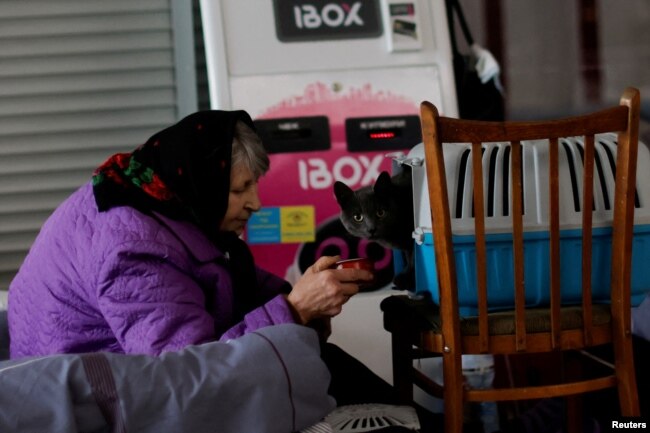 A woman feeds a cat in a complex converted to a temporary shelter for people fleeing Russia's invasion of Ukraine, in Dnipro. April 14, 2022. (REUTERS/Ueslei Marcelino)