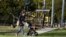 FILE - A woman and child pass a closed playground in Melbourne, Australia, August 17, 2021, as the city battles an outbreak of the Delta variant of coronavirus.