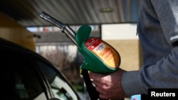 资料照片：2026年3月5日，在英国伦敦，一名顾客在加油站加满油后将油泵放回原处。由于中东冲突，石油和天然气价格飙升。