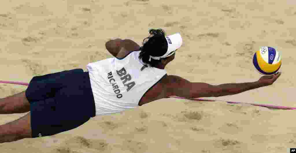 Ricardo Santos, de Brasil, salva la pelota durante un partido de vóleibol playa contra Gran Bretaña.