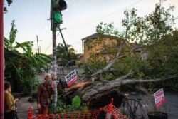 Olivia Mancing and Zachery Quale talk outside Flora Gallery and Coffee Shop near a downed tree in the street after Hurricane Zeta swept through New Orleans, Oct. 29, 2020.