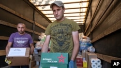 Voluntarios descargan ayuda humanitaria para las personas evacuadas de un combate entre fuerzas rusas y ucranianas en la región de Kursk, en un centro de residencia temporal en Kursk, Rusia, el 11 de agosto de 2024