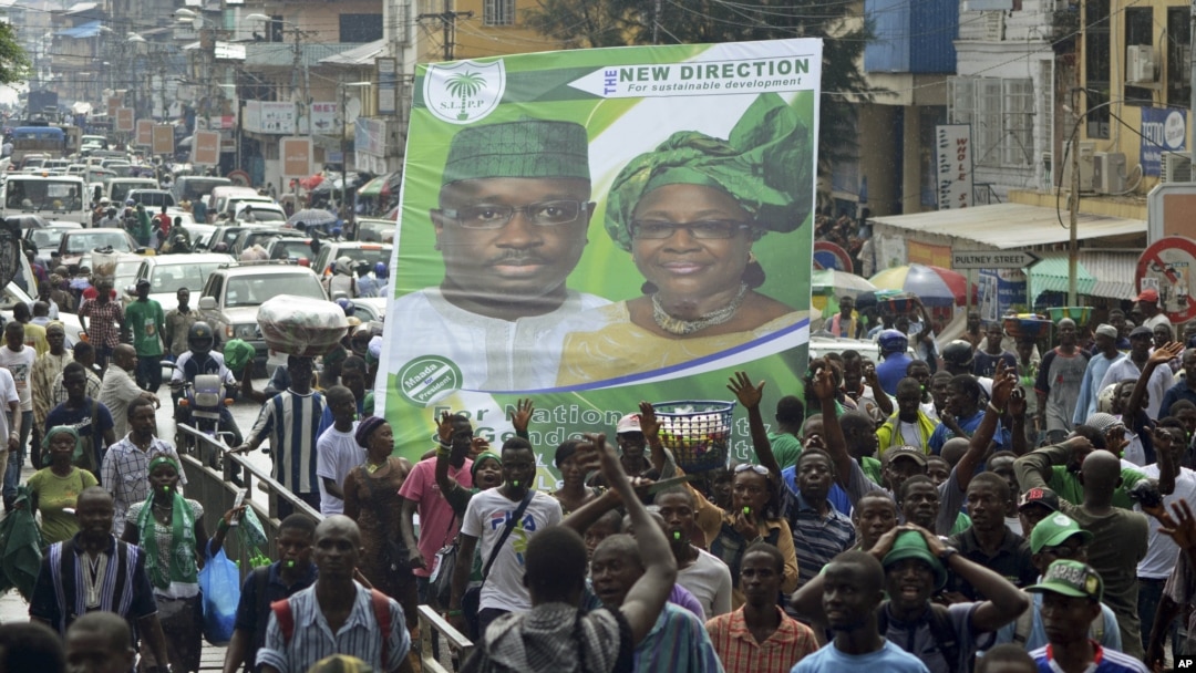 Supporters of the opposition Sierra Leone People's Party (SLPP) march through central Freetown with a placard of presidential candidate Julius Maada Bio and his running mate, Dr. Kadi Sesay, in Freetown, Sierra Leone, October 19, 2012. 