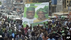 Supporters of the opposition Sierra Leone People's Party (SLPP) march through central Freetown with a placard of presidential candidate Julius Maada Bio and his running mate, Dr. Kadi Sesay, in Freetown, Sierra Leone, October 19, 2012. 