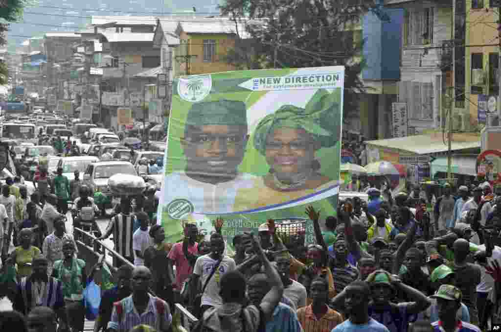 Supporters of the opposition Sierra Leone People's Party (SLPP) march through central Freetown with a placard of presidential candidate Julius Maada Bio and his running mate, Dr. Kadi Sesay, in Freetown, Sierra Leone, October 19, 2012. 