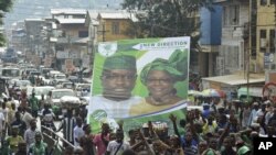 Supporters of the opposition Sierra Leone People's Party (SLPP) march through central Freetown with a placard of presidential candidate Julius Maada Bio and his running mate, Dr. Kadi Sesay, in Freetown, Sierra Leone, October 19, 2012. 