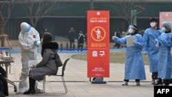 A medical staff member (L) wearing protective gear takes a swab from a visitor to test for the COVID-19 coronavirus at a temporary testing station outside the City Hall in Seoul on December 23, 2020, as South Korea banned gatherings of more than four peop