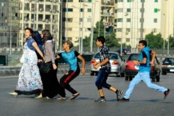 FILE - In this Aug. 20, 2012 photo, an Egyptian youth, trailed by his friends, gropes a woman crossing the street with her friends in Cairo, Egypt.