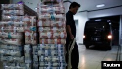 Seorang petugas menunggu untuk mengangkut uang rupiah ke kendaraan di kantor pusat Bank Mandiri, Jakarta (18/11). (Reuters/Darren Whiteside)