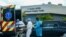 Un enfermo de coronavirus en Miami llega en ambulancia a un hospital especializado, mientras otro es sacado en un carro fúnebre.