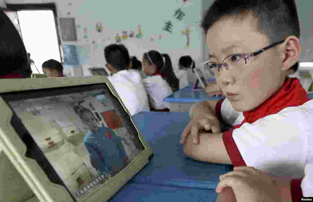 A student looks at his iPad as his class watches a live broadcast of a lecture given by astronauts from the Tiangong-1 space module, at a primary school in Quzhou, Zhejiang province, China, June 20, 2013. 