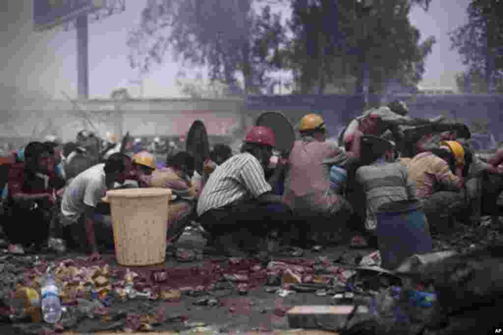 Supporters of ousted President Morsi take cover from Egyptian security forces fire during clashes in Cairo's Nasr City.