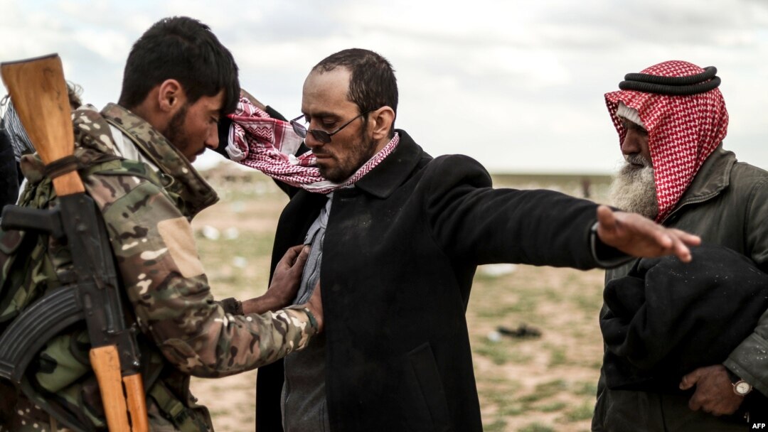 Para pria yang dicurigai anggota kelompok militan ISIS sedang diperiksa oleh anggota Pasukan Demokratik Suriah (SDF) yang dipimpin oleh Kurdi, setelah meninggalkan wilayah pertahanan terakhir ISIS, Baghuz, di Provinsi Deir Ezzor, 27 Februari 2019.
