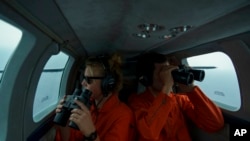 German volunteers Leona Blankenstein, left, and David Lohmueller search from aboard the Seabird for migrant boats in distress as they fly over the Mediterranean Sea between Libya and the Italian island of Lampedusa, Oct. 5, 2021.