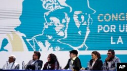 Leaders of the Revolutionary Armed Forces of Colombia (FARC), sit before former guerrillas as they lead the FARC's National Congress where they launched their political party in Bogota, Colombia, Aug. 27, 2017. The former leftist rebels have chosen a familiar-sounding acronym for their political movement: FARC, which now stands for "Common Alternative Revolutionary Force."