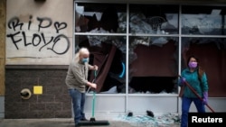 People clean up outside a local business in the area in the aftermath of a protest after a white police officer was caught on a bystander's video pressing his knee into the neck of African-American man George Floyd, who later died at a hospital, in Minnea